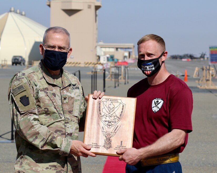 U.S. Army Capt. Sam DeBold, right, support operations officer with Headquarters Support Company, 628th Aviation Support Battalion, 28th Expeditionary Combat Aviation Brigade, receives a handmade plaque from Col. Howard Lloyd, 28th ECAB commander, for being the top finisher in the Task Force Anvil Marathon. About 120 Soldiers raced in memory of Michael J. Novosel, Sr., a native of Etna, Pennsylvania, who served for over 40 years as an Army aviator and received the Medal of Honor for rescuing 29 Soldiers during the Vietnam War.