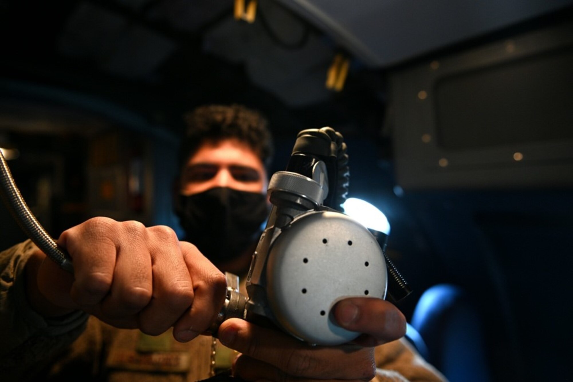 An Airman in a mask works electronics on a headset