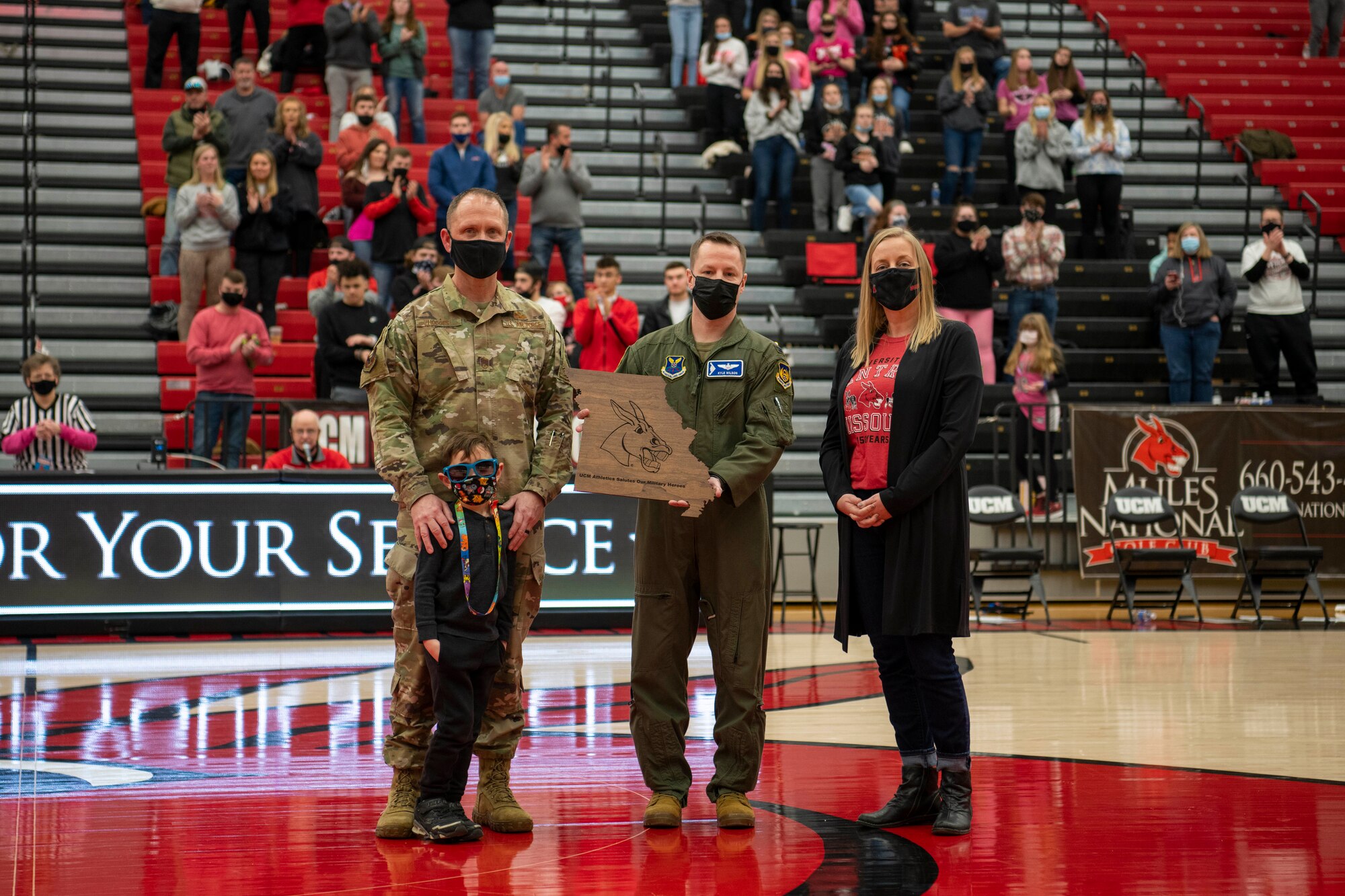 U.S. Air Force Chief Master Sgt. Jason Hodges, 509th Bomb Wing command chief, left, Col. Kyle Wilson, 509th BW vice commander, center, and Lindsay Chapman, University of Central Missouri general counsel, pose for a photo during a recognition ceremony of the UCM Military Appreciation basketball game, Feb. 13, 2021, in Warrensburg, Missouri. Whiteman AFB and UCM share a valuable community partnership that fosters a supportive relationship between the base and local communities. (U.S. Air Force photo by Tech. Sgt. Dylan Nuckolls)