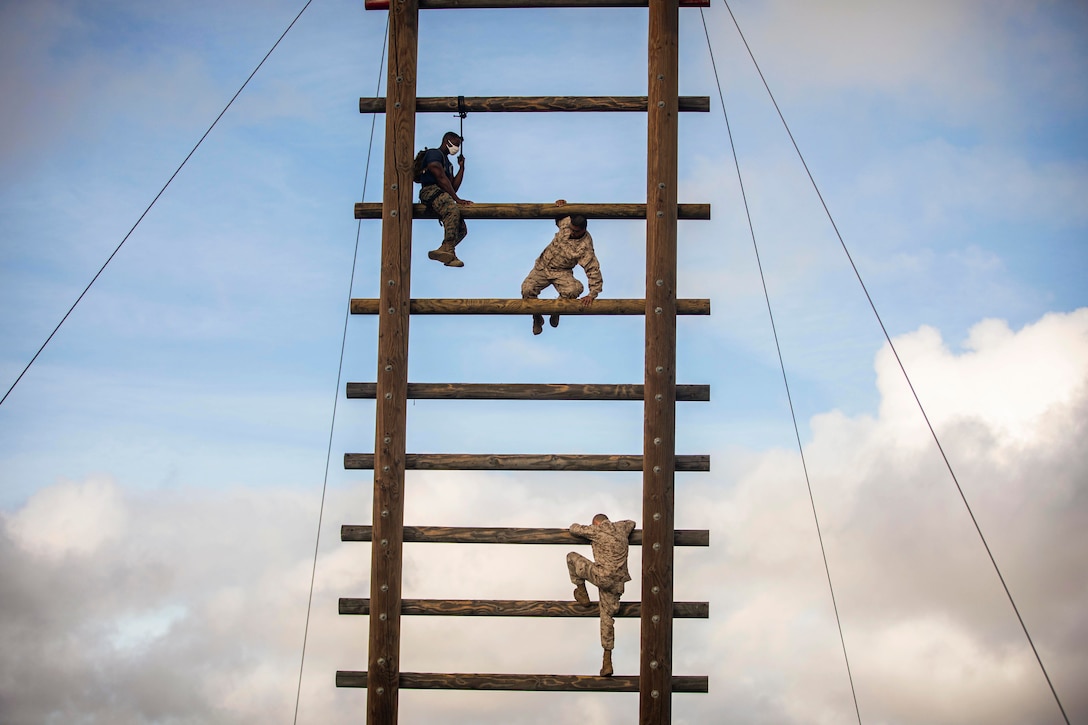 Marine Corps recruits climb a ladder.