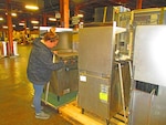 A warehouse worker prepares kitchen equipment for movement.