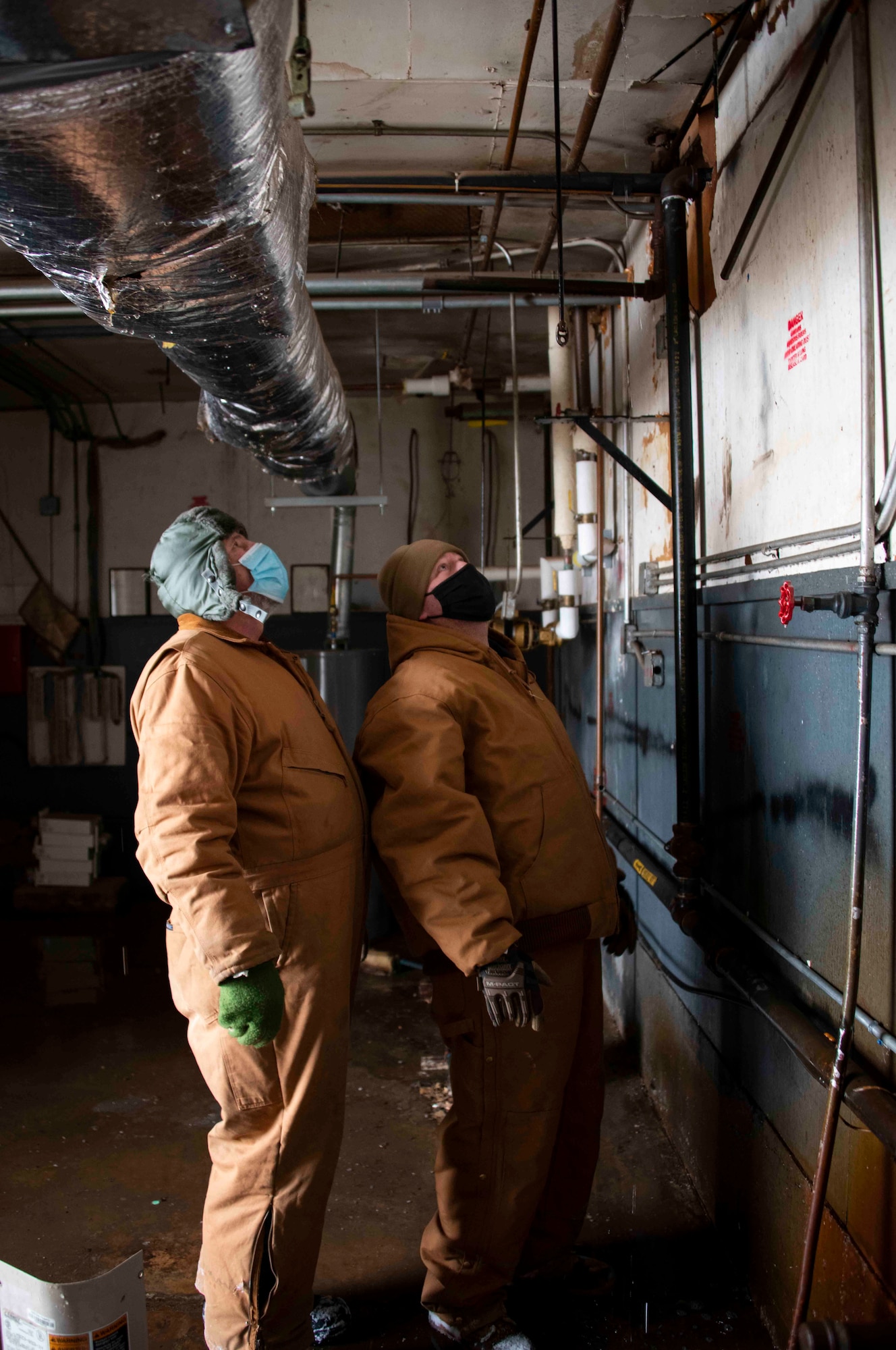 From left, Greg Miller, 97th Civil Engineer Squadron (CES) engineering technician, and Tech. Sgt. Michael Richardson, 97th CES section chief of water and fuel systems maintenance, observe a leak, Feb. 16, 2021, at Altus Air Force Base, Oklahoma. The pipe burst due to freezing temperatures, causing areas of the facility to flood. (U.S. Air Force photo by Airman 1st Class Amanda Lovelace)