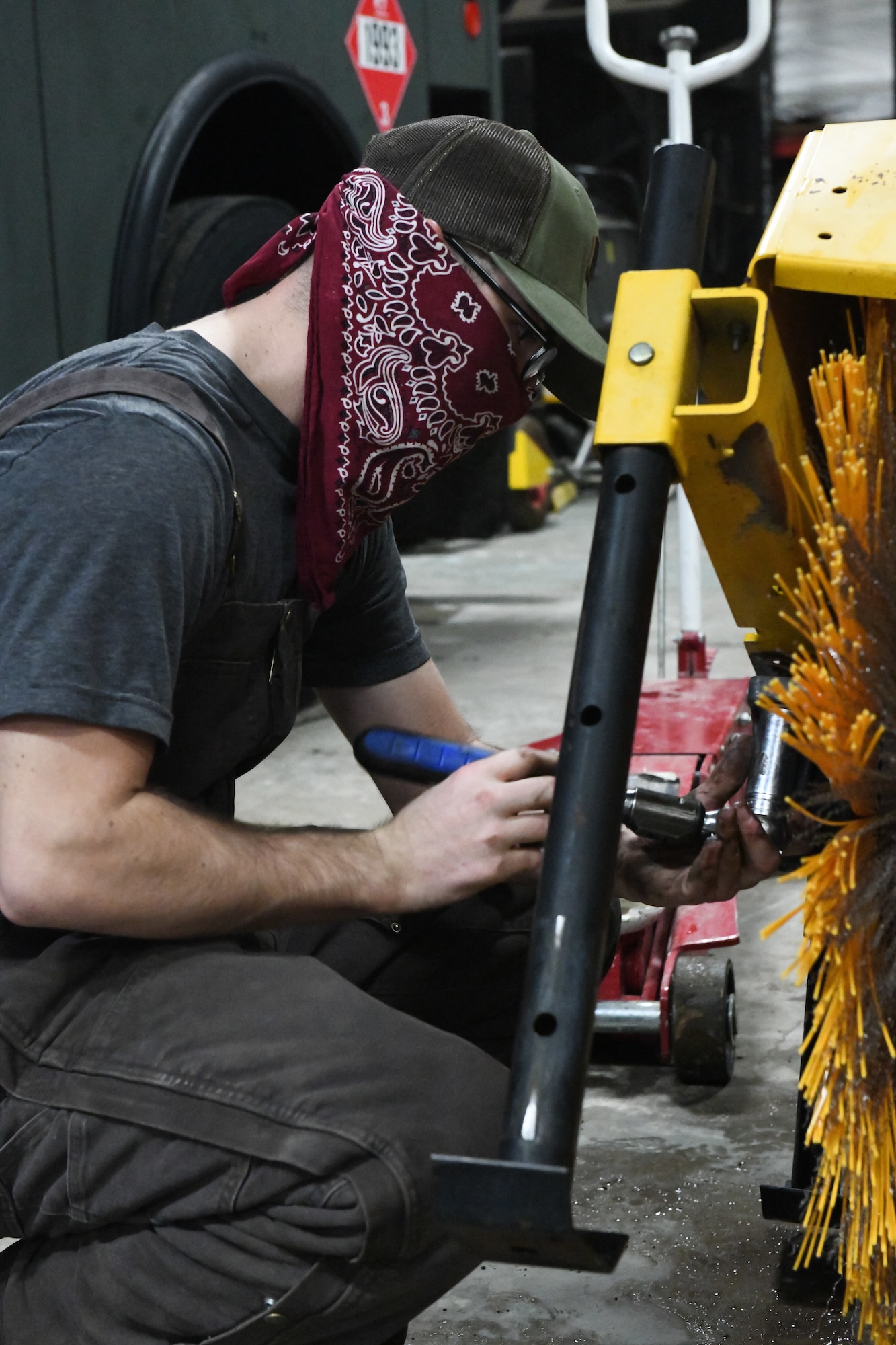 man replaces brushes on snow removal equipment