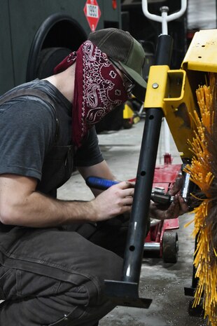 man replaces brushes on snow removal equipment