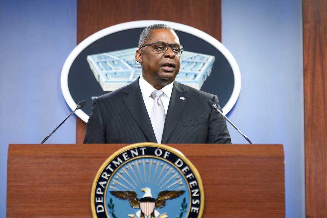 Secretary of Defense Lloyd J. Austin III stands and speaks at a lectern.