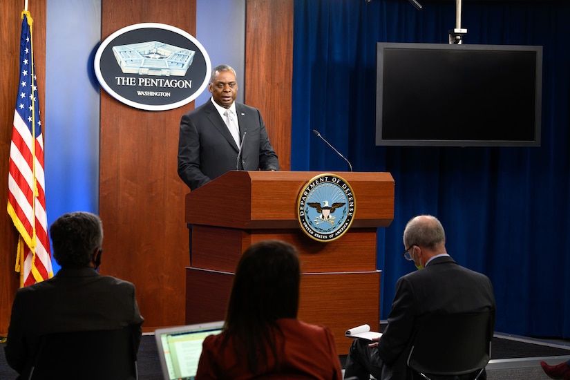 Secretary of Defense Lloyd J. Austin III stands and speaks at a lectern to seated audience members.