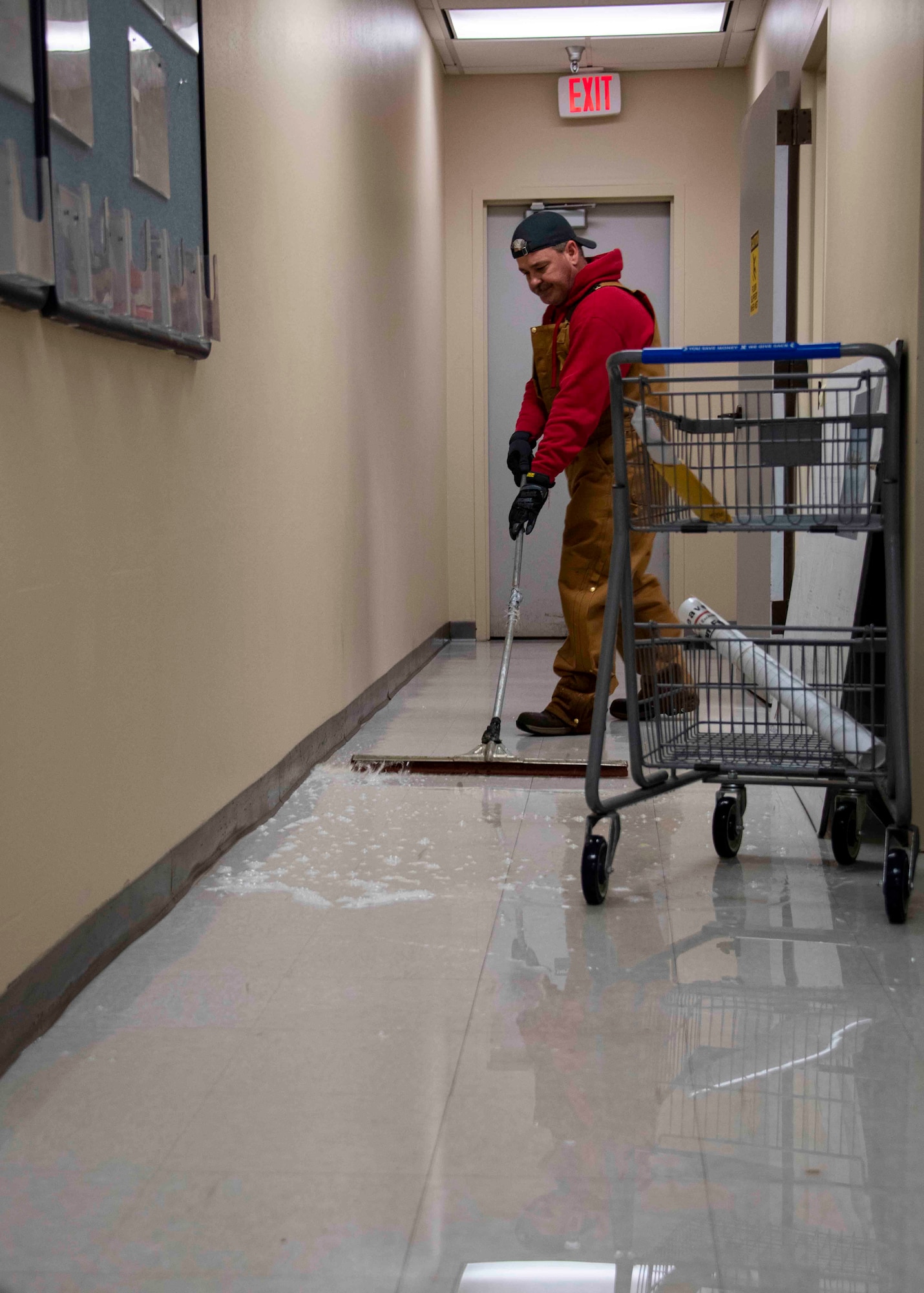 Thomas Sturdevant, a 97th Civil Engineer Squadron maintenance mechanic, pushes water from a hallway, Feb. 16, 2021, at Altus Air Force Base, Oklahoma. Members of 97th CES responded to several burst water pipes across Altus AFB caused by freezing temperatures. (U.S. Air Force photo by Airman 1st Class Amanda Lovelace)