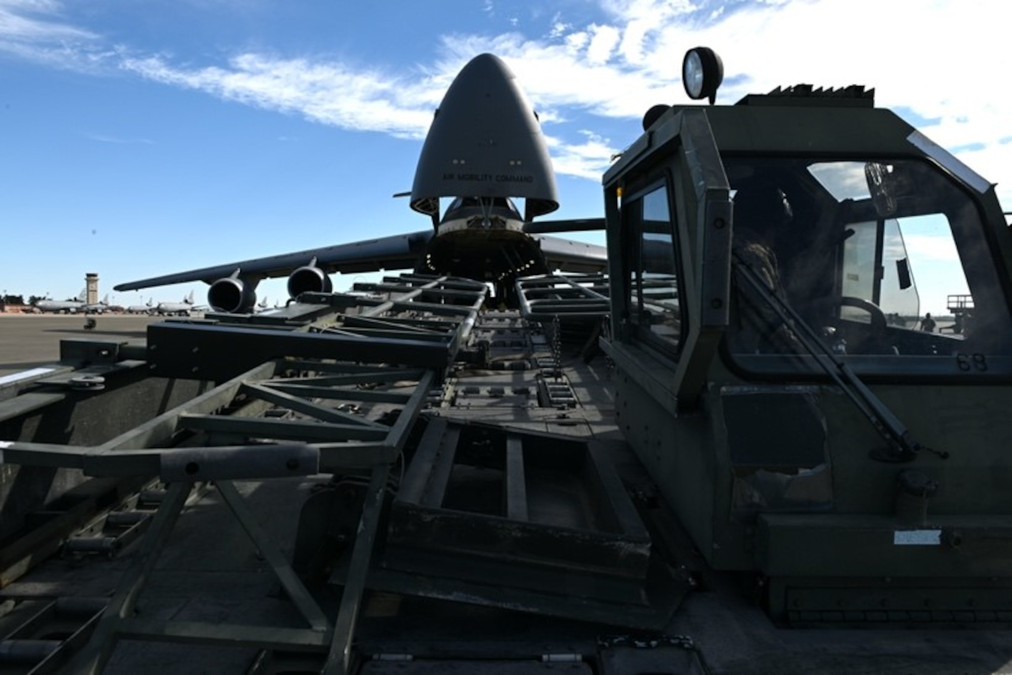 A K loader is positioned in front of the gaping maw of a C-5M Super Galaxy
