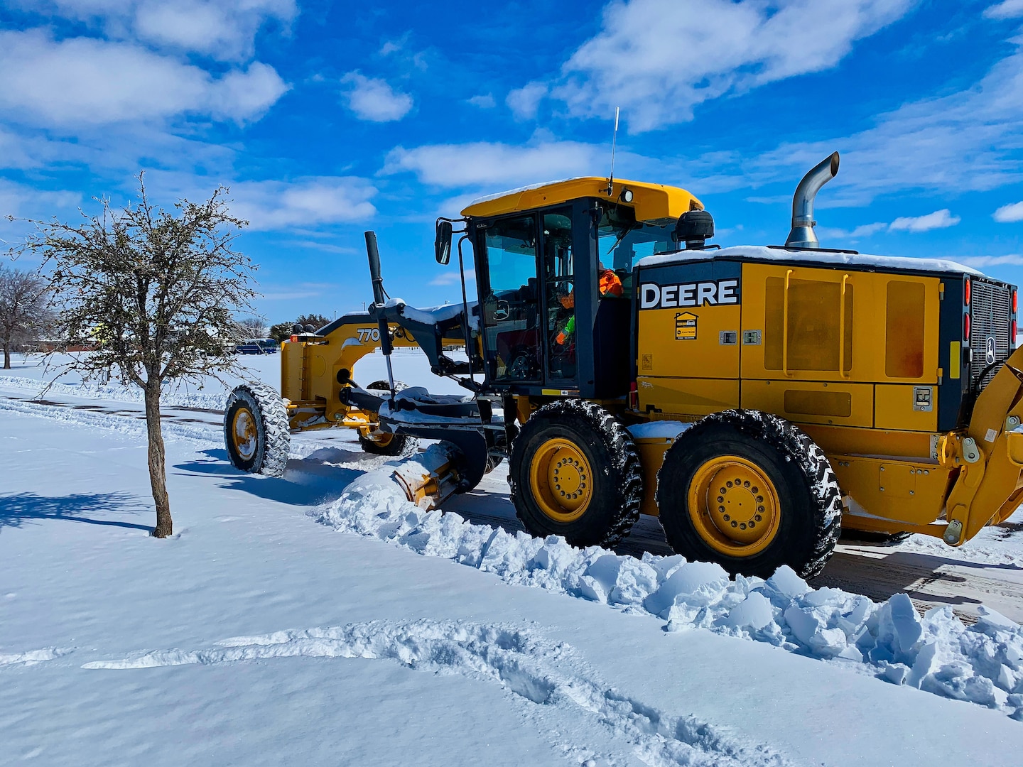 A member of the 17th Civil Engineering Squadron enhances the safety of the travel routes throughout the base by clearing snow on Goodfellow Air Force Base, Texas, Feb. 15, 2021. The 17th CES adapted and overcame the challenges of record-breaking snowfall with no proper removal equipment in order to continue the mission. (Courtesy photo)