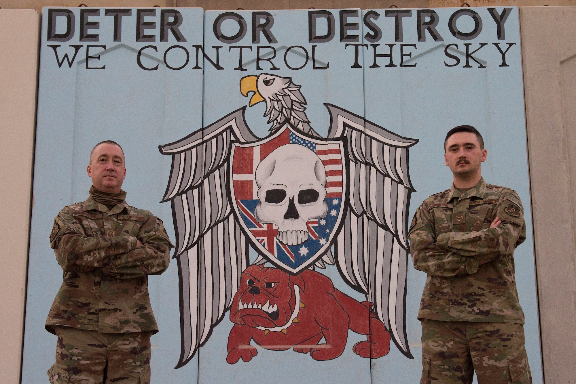 U.S. Air Force Master Sgt. Heath McCoppin, 727th Expeditionary Air Control Squadron air surveillance and electronic protection technician (left), and Senior Airman Garrett McCoppin, 727th EACS cyber operations technician (right), pose for a photo at Al Dhafra Air Base, United Arab Emirates, Jan. 25, 2021.