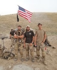 Three men stand with equipment on a hill