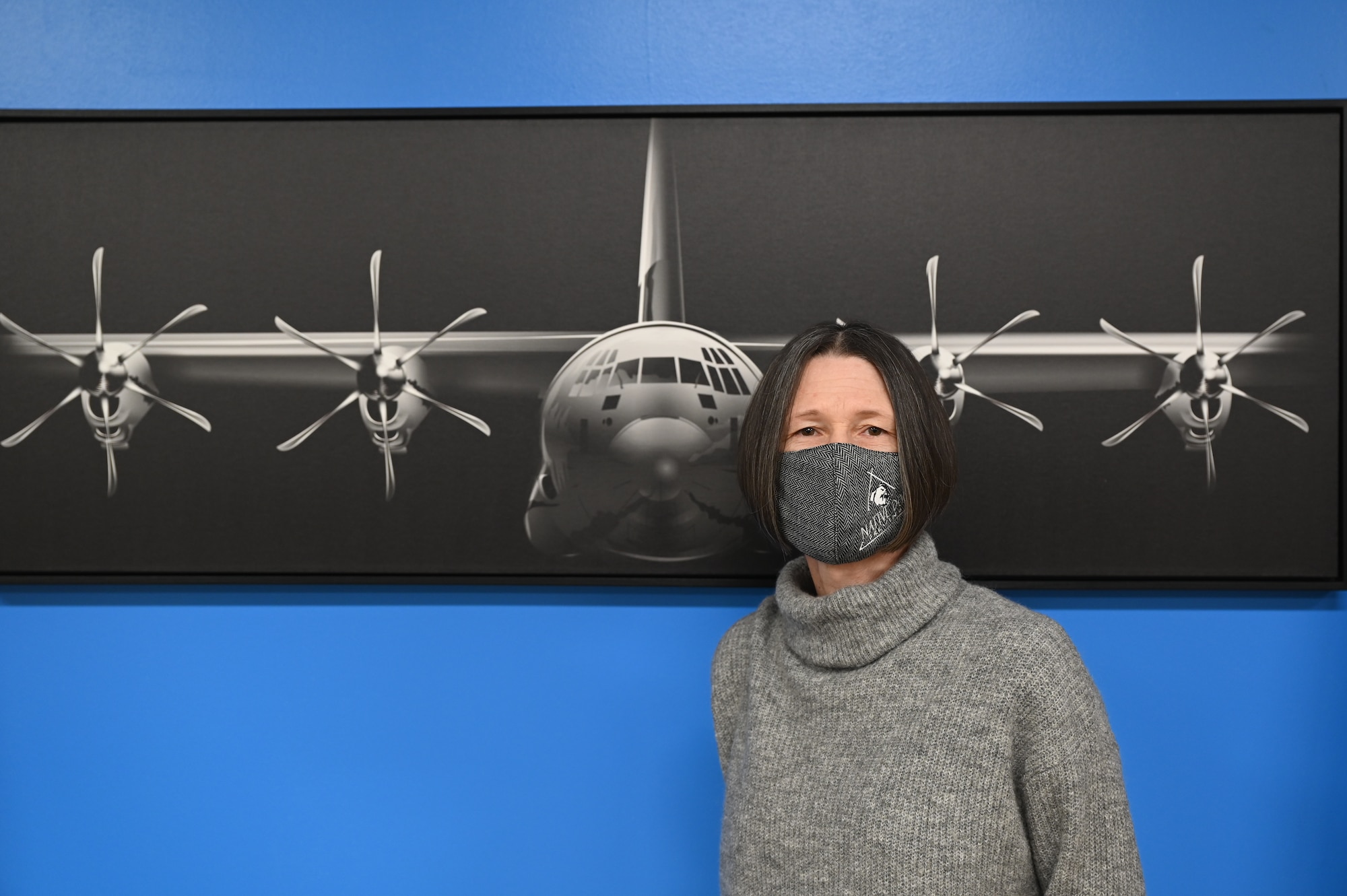 A Civilian contractor poses for a photo in front of a C-130 print.