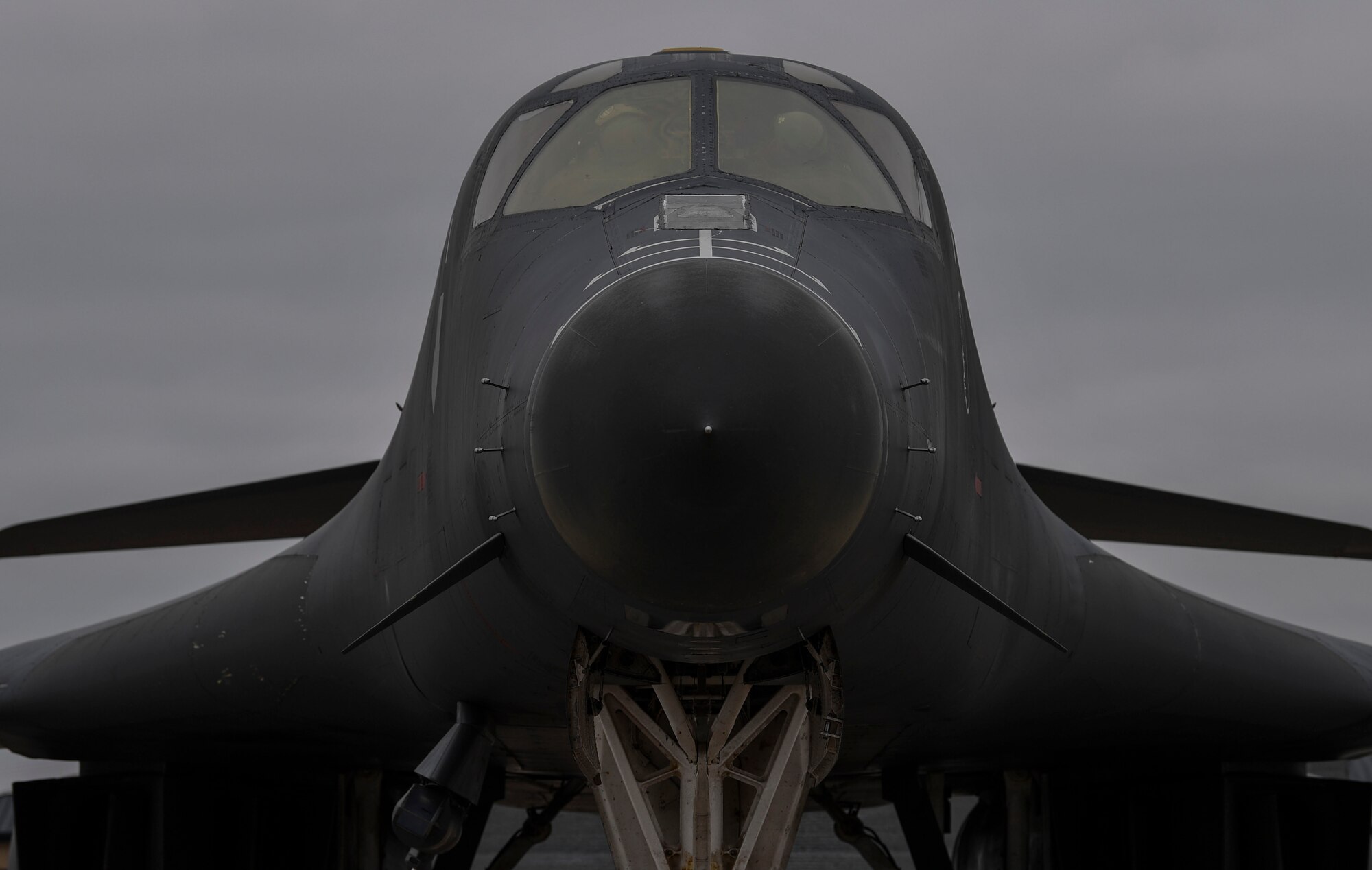 Two pilots seen through the windows of a B-1 Lancer make final preparations for a flight.