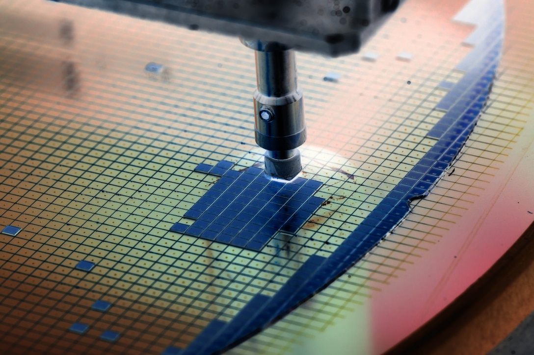 A metal instrument touches the surface of a flat grid.