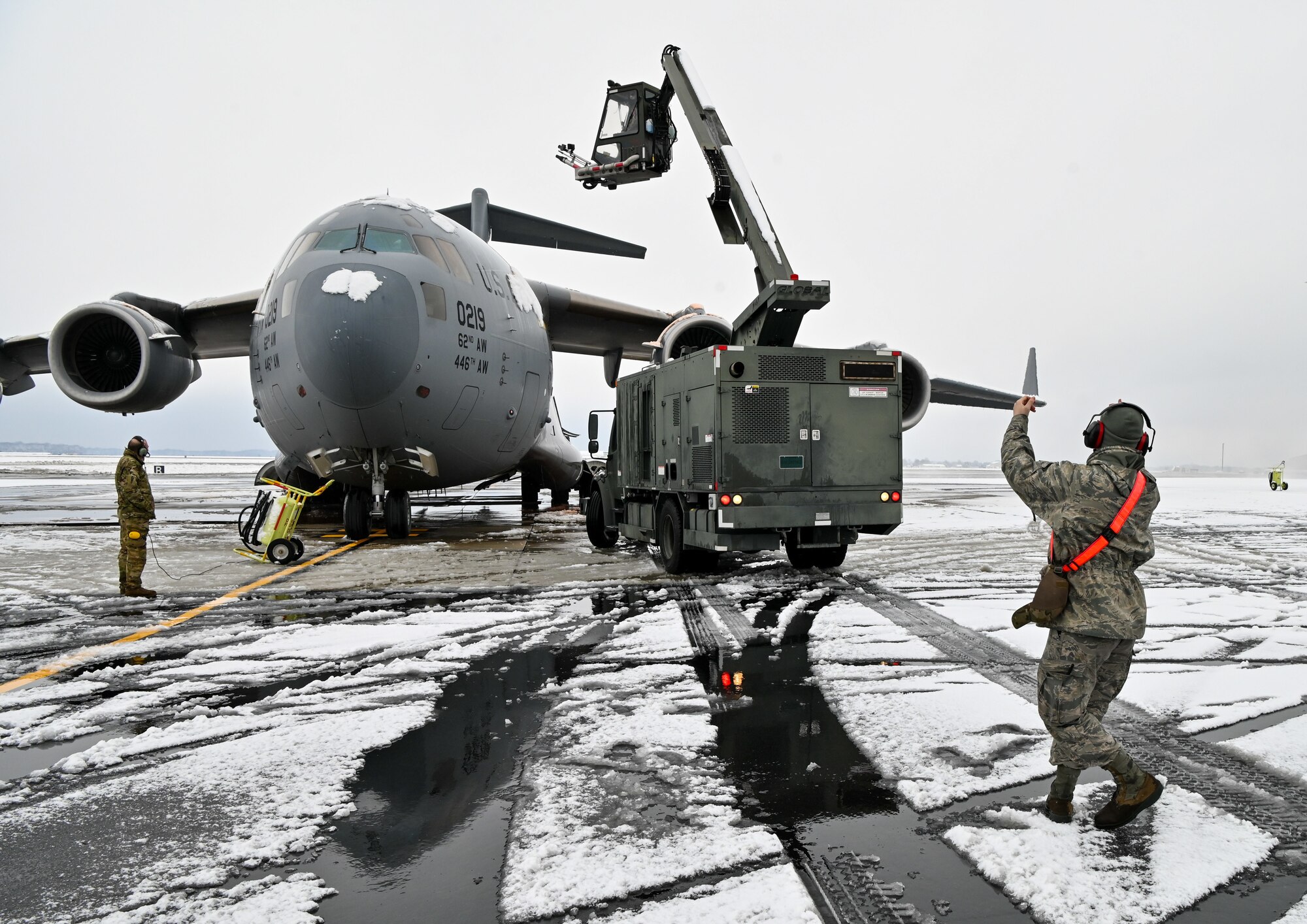 An aircraft de-icing team marshals a de-icing vehicle at Dover Air Force Base, Delaware, Feb. 11, 2021. Because snow and ice can change the shape of an aircraft's wings and tail, the de-icing process is very important in ensuring a smooth and safe flight. (U.S. Air Force photo by Senior Airman Christopher Quail)