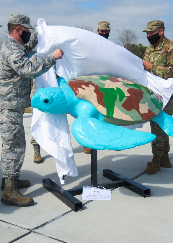 U.S. Air Force Senior Airmen Joshua Aquino, 325th Maintenance Squadron armament technician, left, and Raymundo Hernandez, 81st Air Control Squadron interface control technician, right, unveil a sculpture the Tyndall Active Airmen Association painted at a ceremony hosted in Panama City Beach, Florida, Feb. 19, 2021. The TAAA painted a sculpture in the form of a sea creature, “Turbo the Turtle,” which was a part of a local resiliency initiative supported by Panama City Beach, highlighting the tie between the community and Tyndall Air Force Base Airmen. (U.S. Air Force photo by Staff Sgt. Magen M. Reeves)