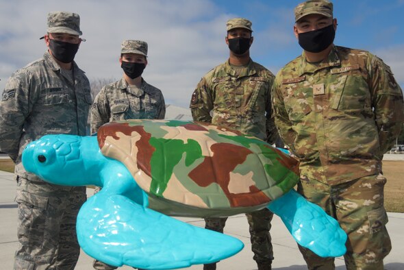 (From left to right) U.S. Air Force Senior Airman Joshua Aquino, 325th Maintenance Squadron armament technician, Airmen 1st Class Katherine Hanson, 325th Contracting Squadron contract specialist and Tyrone Dowell, 81st Air Control Squadron interface control technician and Senior Airman Raymundo Hernandez, 81st ACS interface control technician, pose for a photo in front of a sculpture the Tyndall Active Airmen Association painted in Panama City Beach, Florida, Feb. 19, 2021. The TAAA participated in an art initiative supported by Panama City Beach and painted a sculpture in the form of a sea creature, “Turbo the Turtle.” The art project epitomized the resiliency of the local community and depicted Tyndall Air Force Base’s strong community alliance. (U.S. Air Force photo by Staff Sgt. Magen M. Reeves)