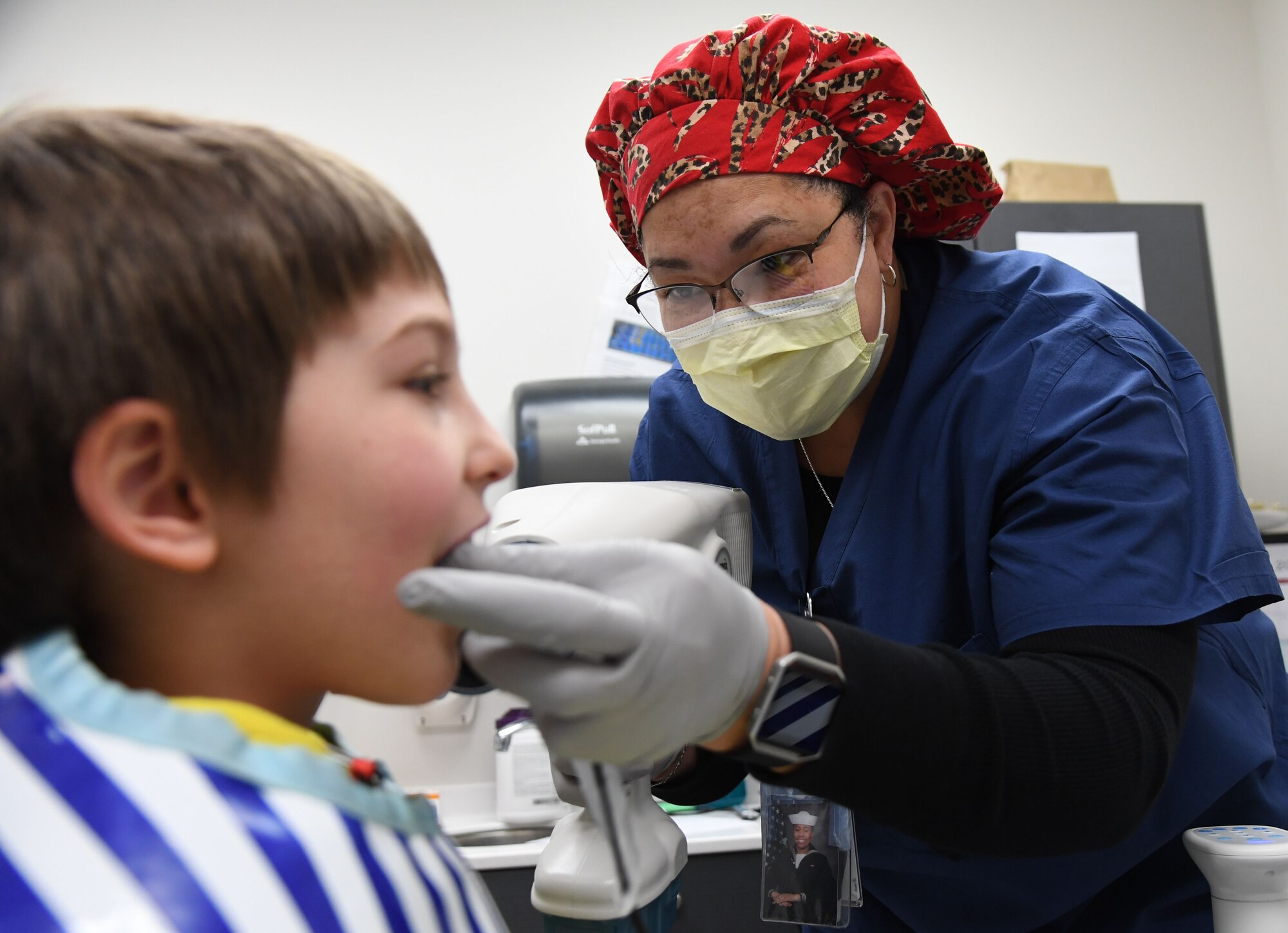 Felicia Harper, 81st Dental Squadron dental technician, conducts an X-ray exam on Tobias Whitfield, son of U.S. Air Force Airman 1st Class James Whitfield, 85th Engineering Installation Squadron radio frequency transmissions technician, during the 10th Annual Give Kids a Smile Day at the dental clinic inside the Keesler Medical Center at Keesler Air Force Base, Mississippi, Feb. 17, 2021. The event was held in recognition of National Children's Dental Health Month and included free dental exams and cleanings for children ages 1-12. (U.S. Air Force photo by Kemberly Groue)