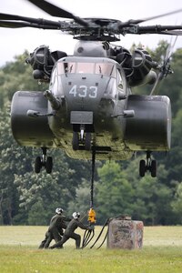 Helicopter hovering over a field to lift supplies