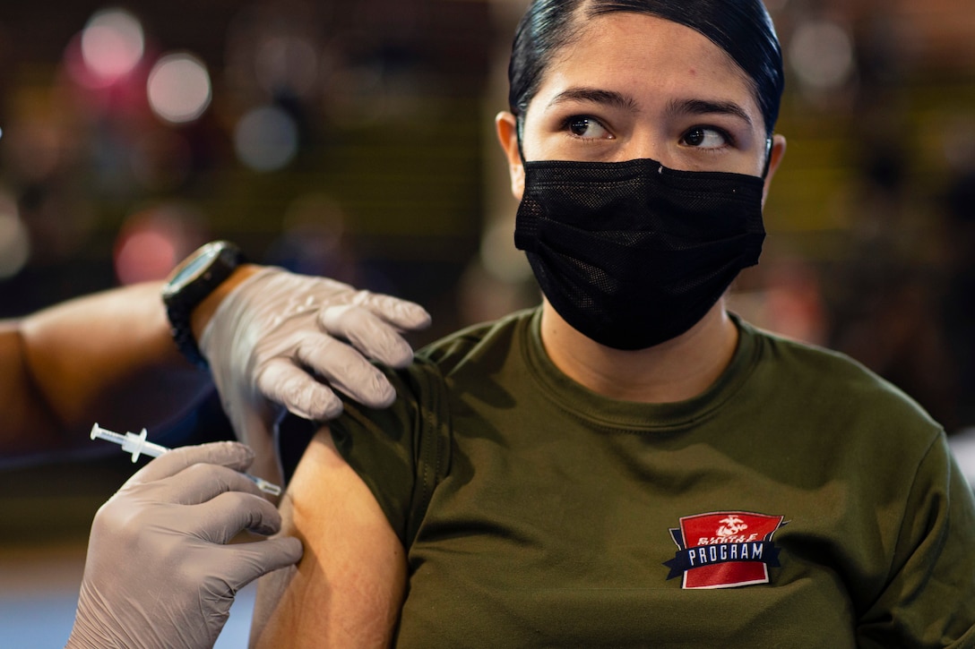A Marine wearing a face mask receives a COVID-19 vaccine