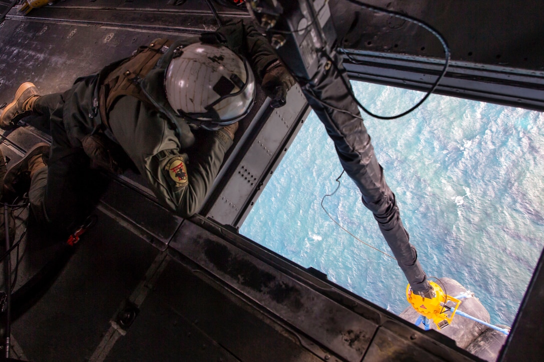 A Marine watches an external lift on a helicopter.