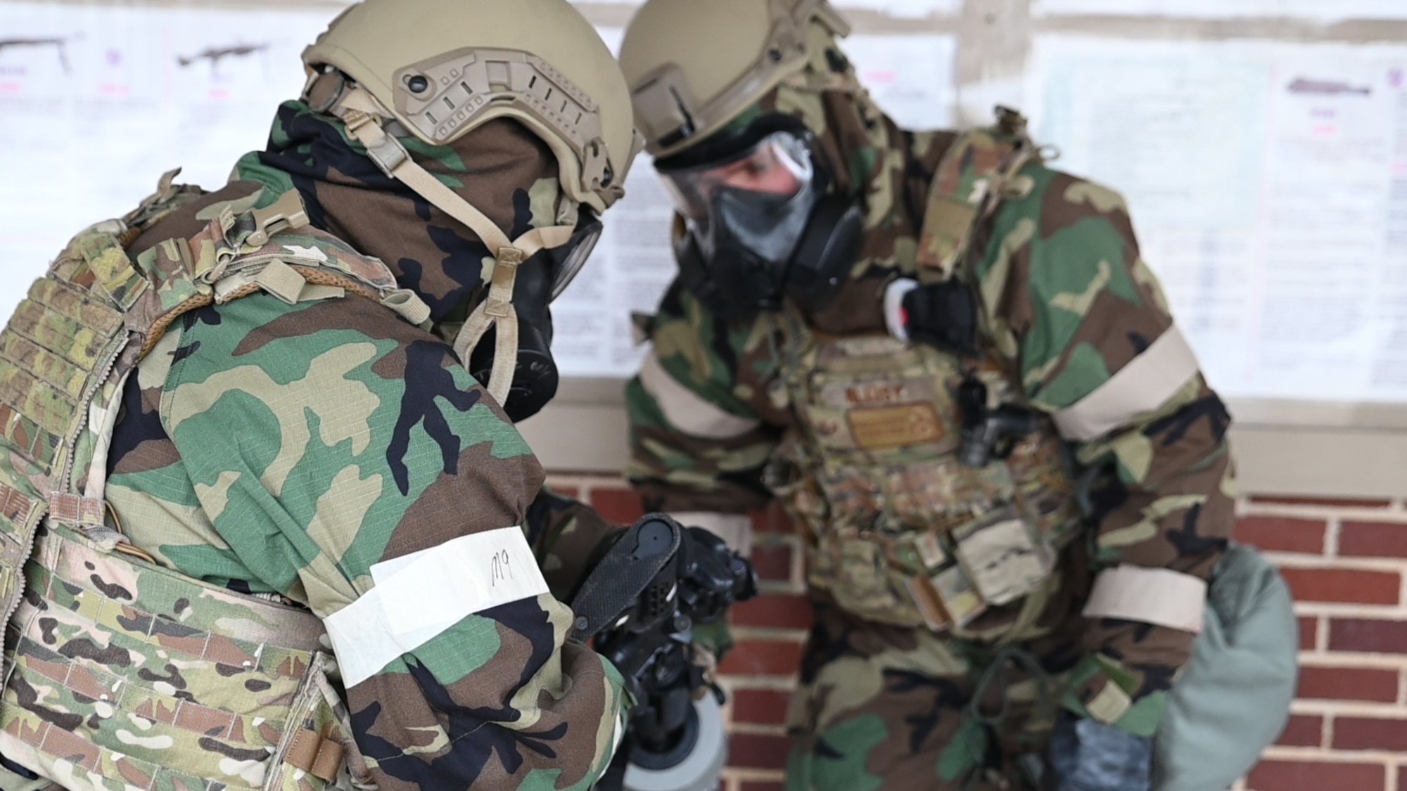 188th Security fForces squadron members inspect an M4 weapon while wearing gas masks.