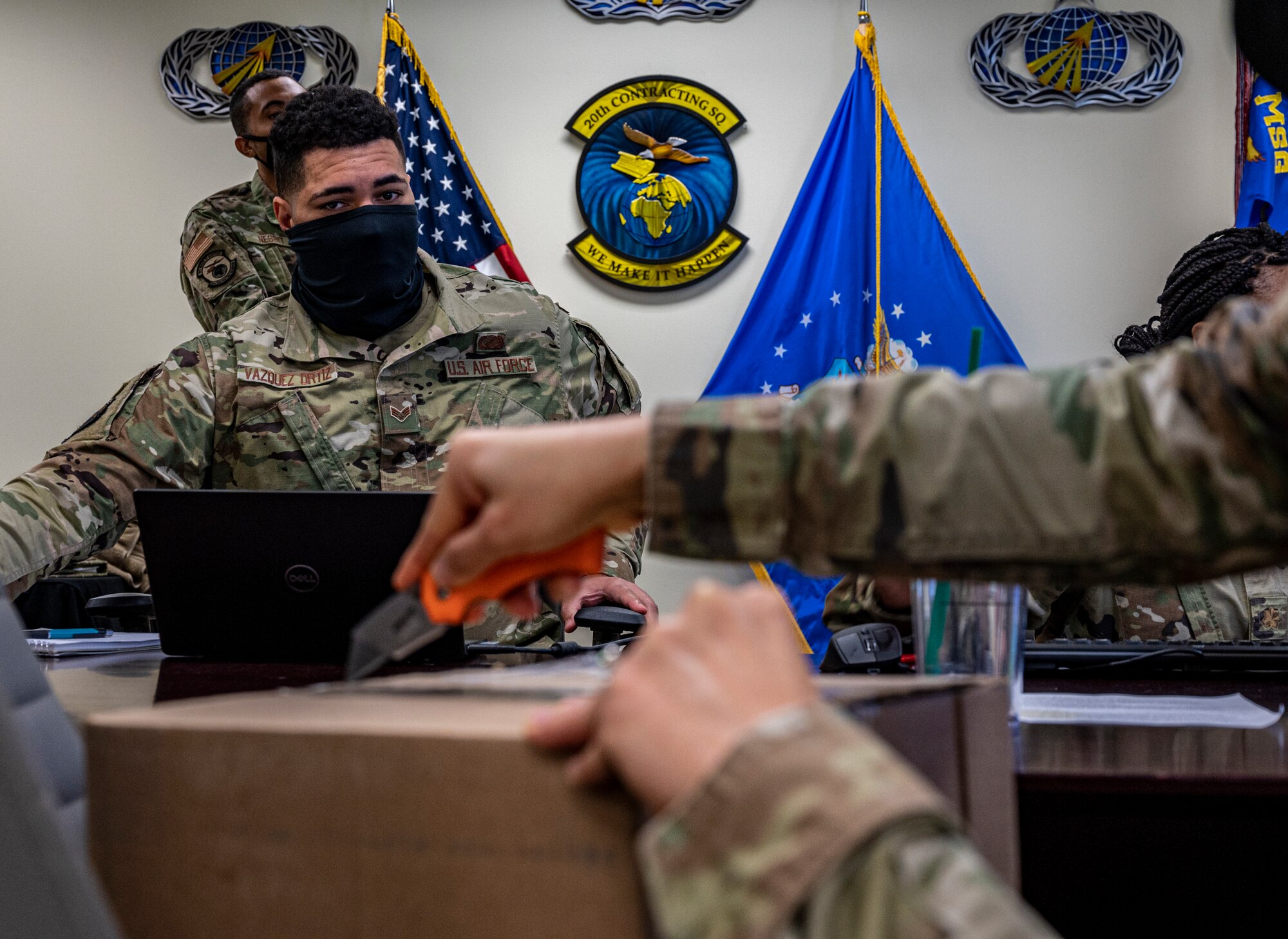 A photo of an Airmen cutting a box with a knife.