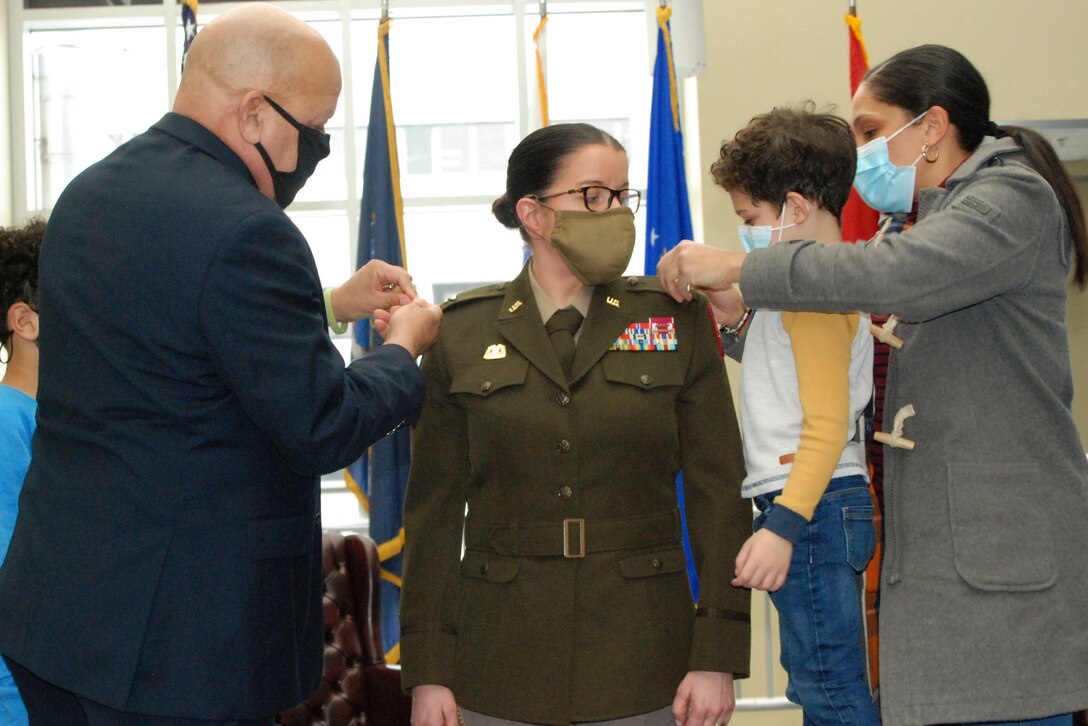 Family members pin a soldier during a ceremony.