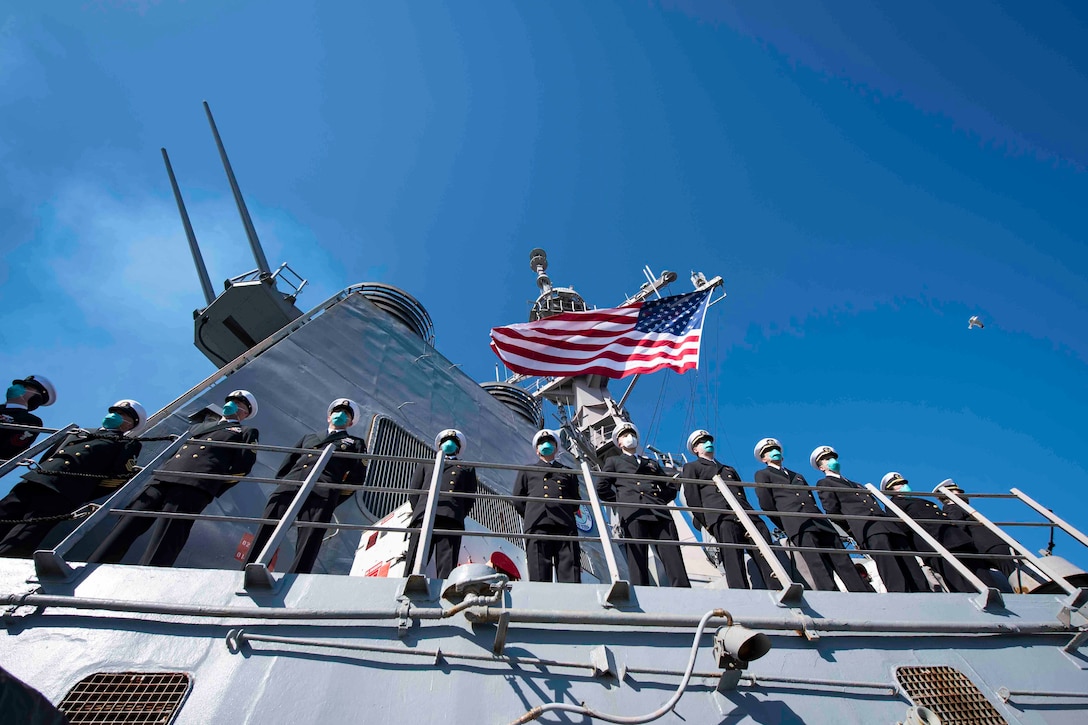 Sailors line up along the rails of a ship.