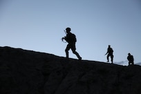 3 soldiers climb a hill at daybreak