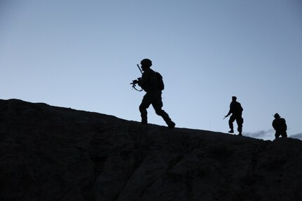 3 soldiers climb a hill at daybreak