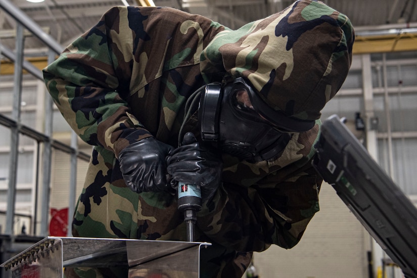 Photo of an Airman removing rivets from sheet metal.