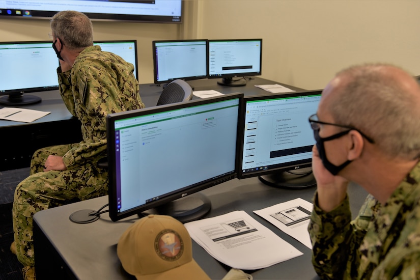 People in uniforms work on computers.