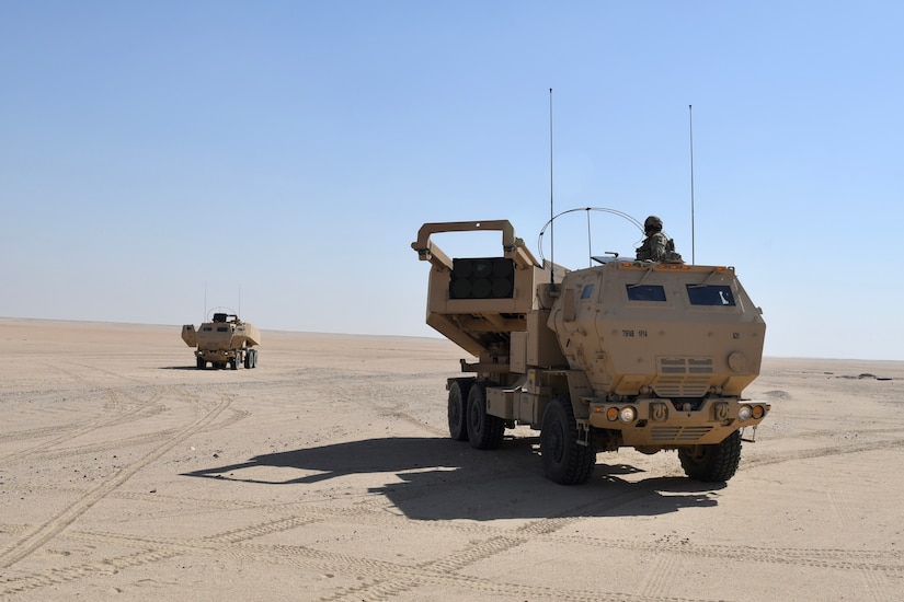 Tactical vehicles advance through desert.