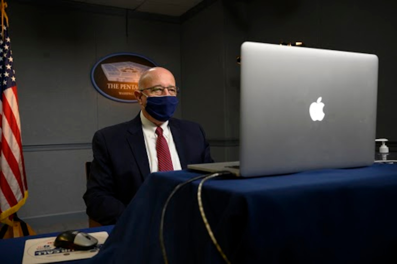 A man speaks virtually at a symposium.