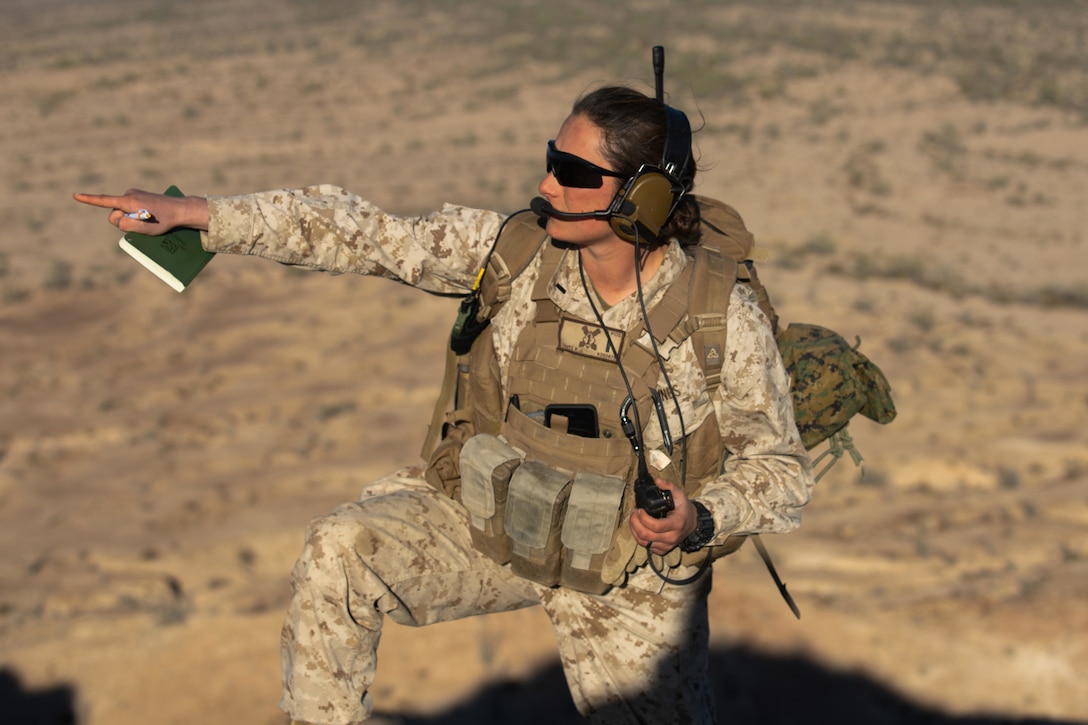 A Marine points to a location during training in a dry open area.