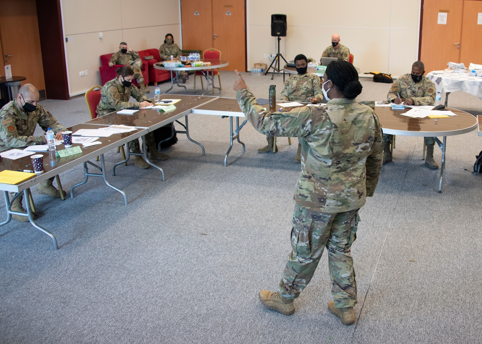 A female officer stands in-front of a small class of officers, talking to them