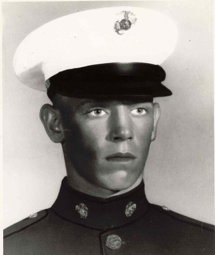 A young man in uniform and cap poses for a photograph.