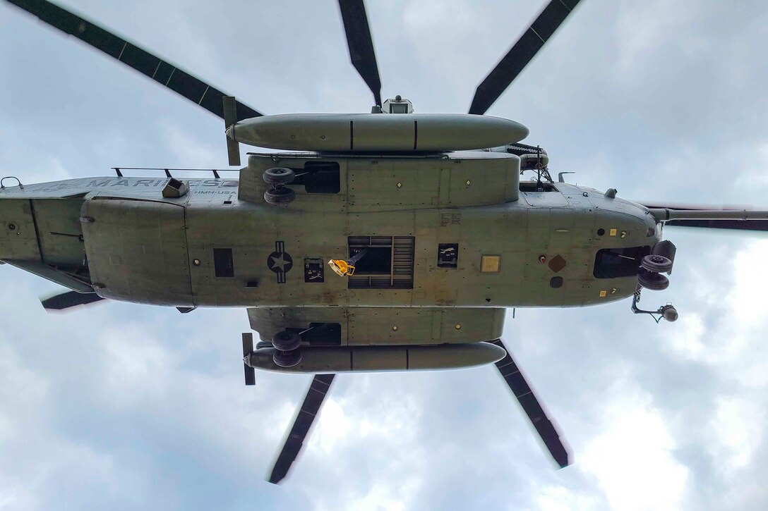The underside of an airborne Marine Corps helicopter is visible from below.