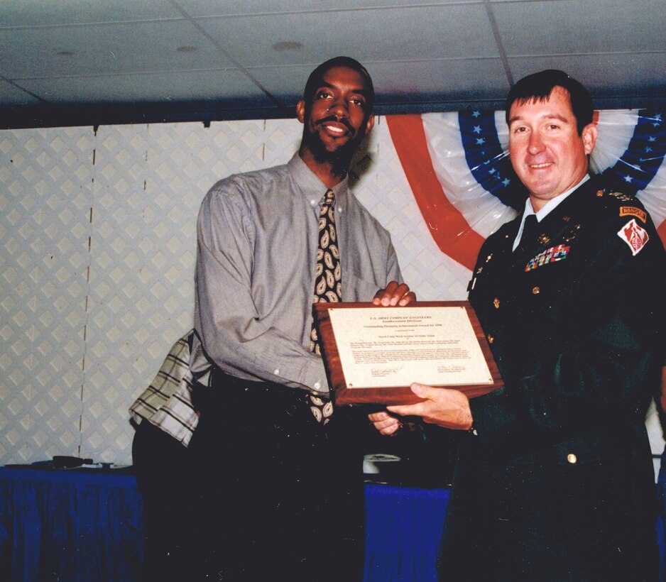 man presenting another man an award while shaking his hand