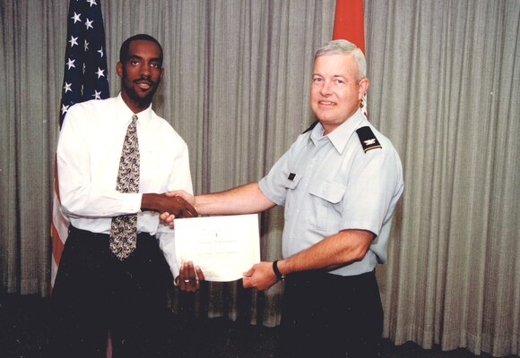 one man in uniform shaking hands with another man while presenting an award