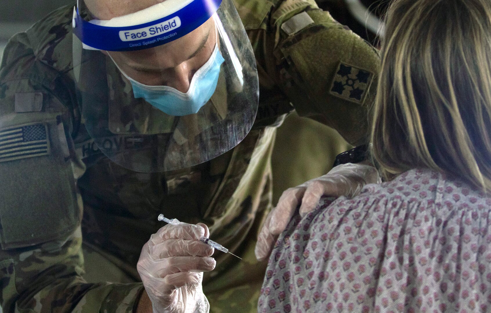 U.S. Army Spc. Jeb Hoover, assigned to the 4th Infantry Division, Fort Carson, Colorado, vaccinates a California community member at the walk-up vaccination site at California State University Los Angeles in California Feb. 20.