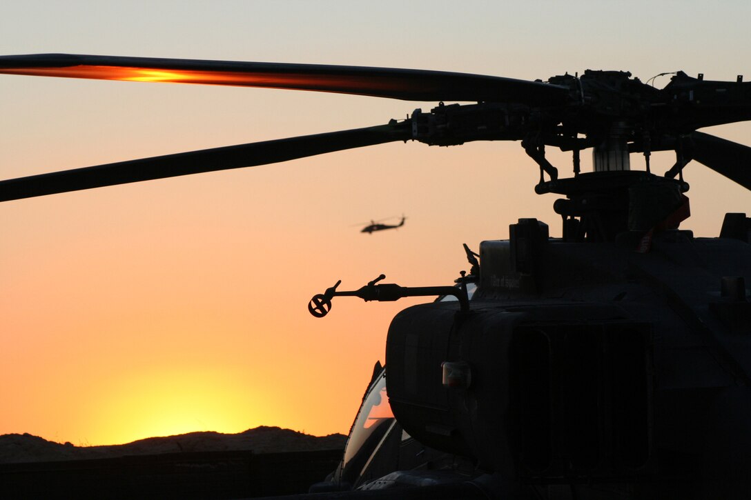 A helicopter sits in silhouette at dusk.