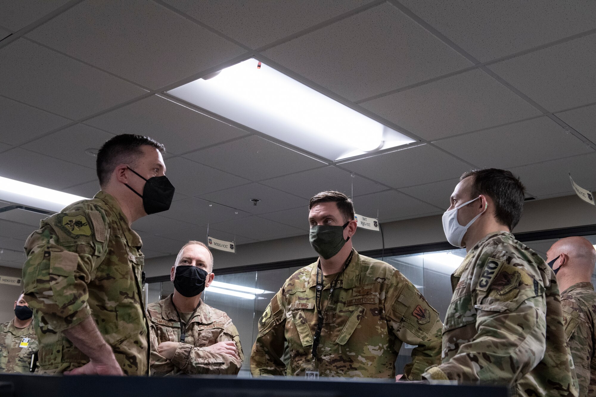 A photo of Airmen standing in a circle talking to each other.