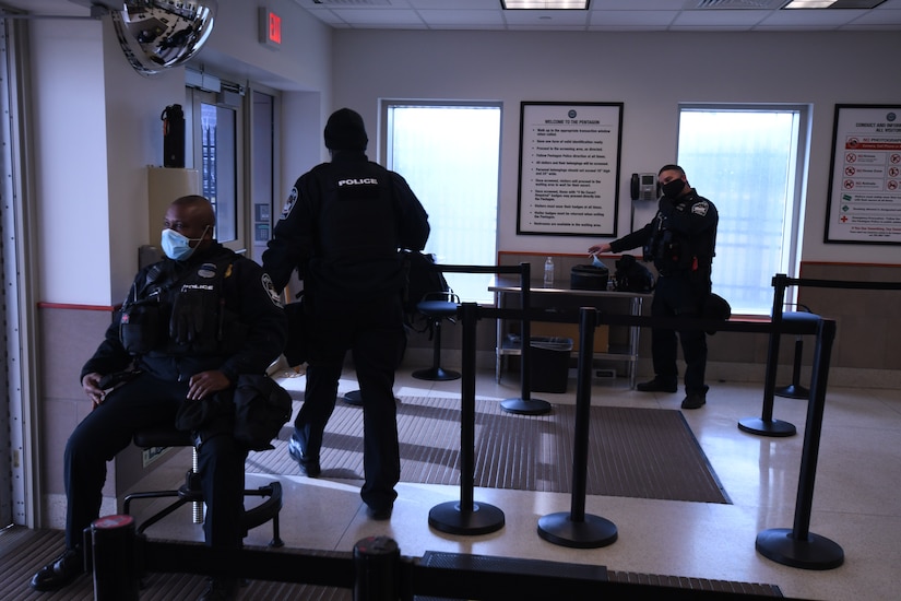 Three police officers check t credentials at the Pentagon’s Visitors Center.