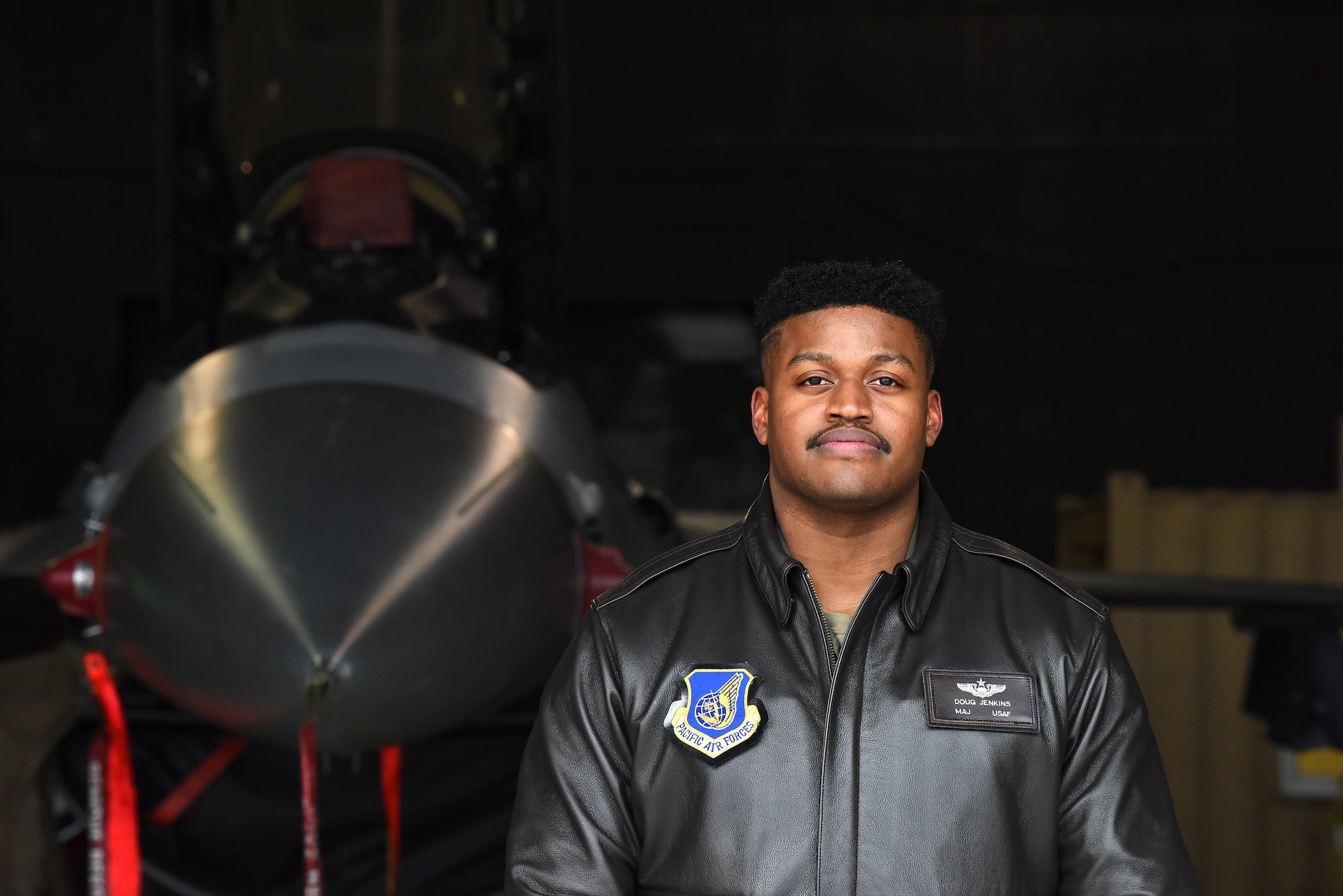 Maj. Douglas "Bane" Jenkins, 8th Fighter Wing Advanced Programs Office program manager, poses for a photo in front of an F-16 Fighting Falcon on the flightline at Kunsan Air Base, Republic of Korea, Feb. 18, 2021. Jenkins decided to become a pilot in the U.S. Air Force after attending ROTC at Tuskegee University from 2006-2011. (U.S. Air Force photo by Senior Airman Suzie Plotnikov)