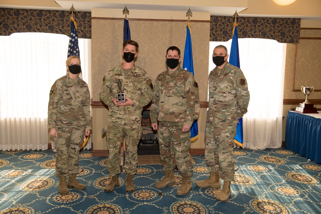 Four Airmen stop for a photo during an awards ceremony
