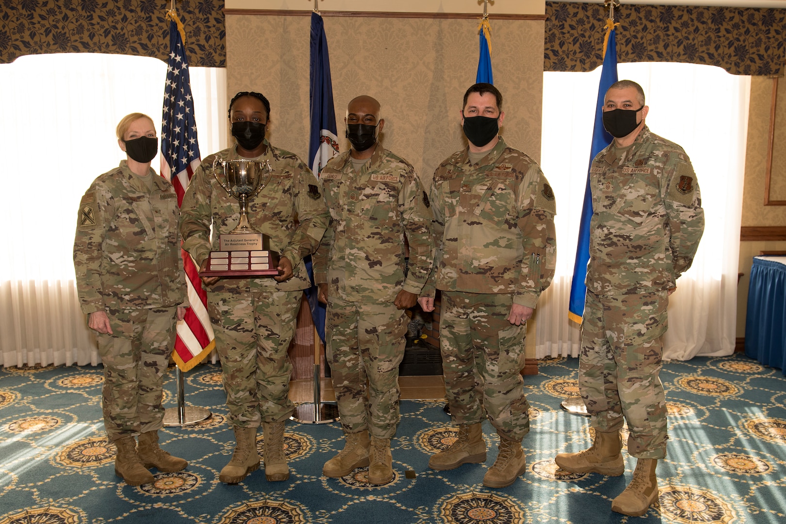 Airman accept a trophy from military leaders during a ceremony