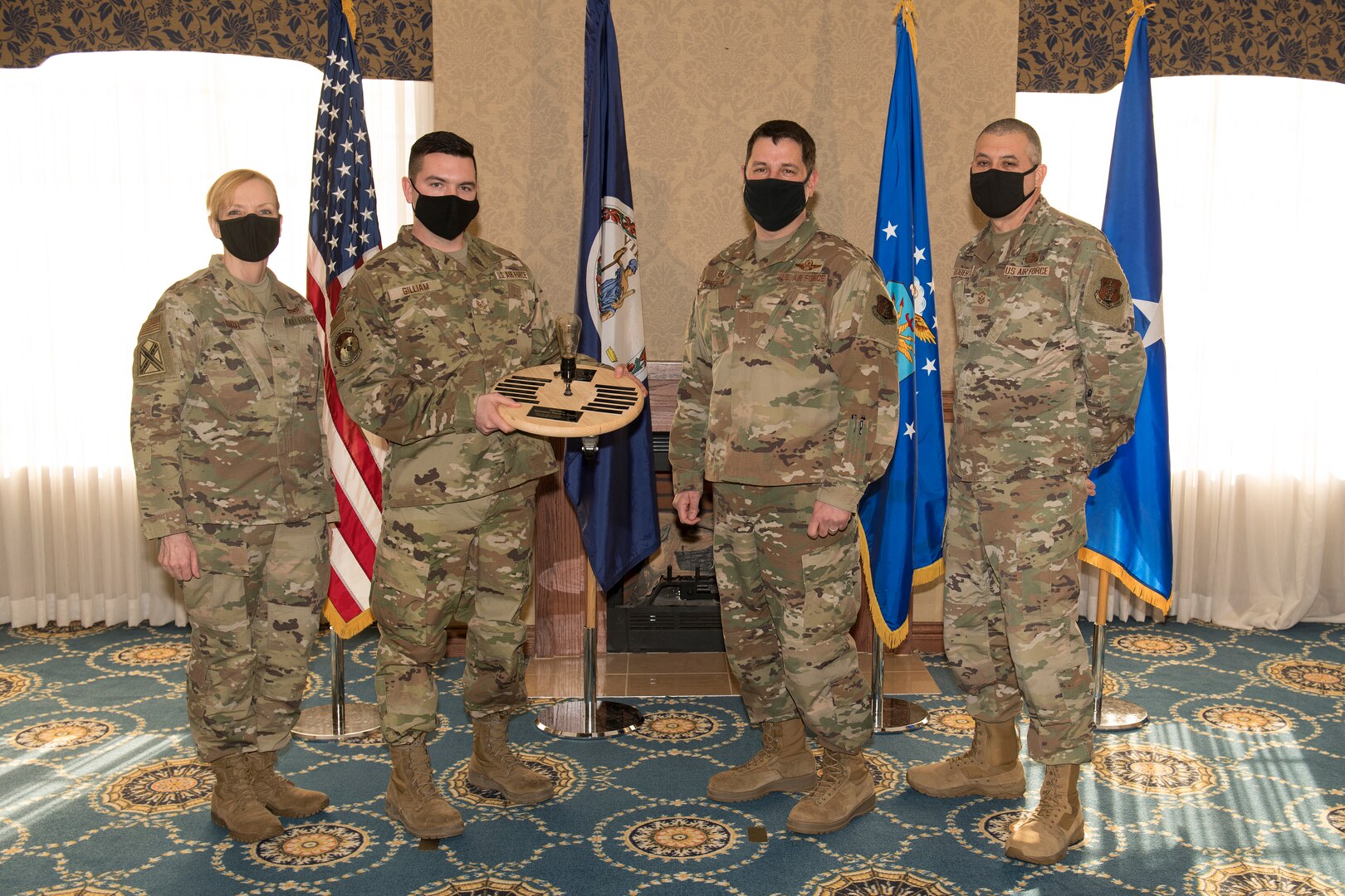 An Airman accepts an award from military leaders during a ceremony