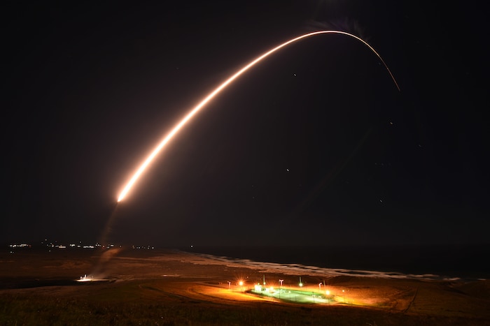 A missile launches from the ground, leaving a trail of fire in the night sky.